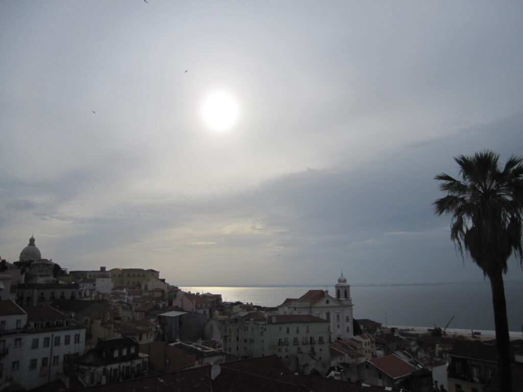 Hillside view over Alfama’s tiled rooftops, with the dome of Santa Engrácia in the distance.