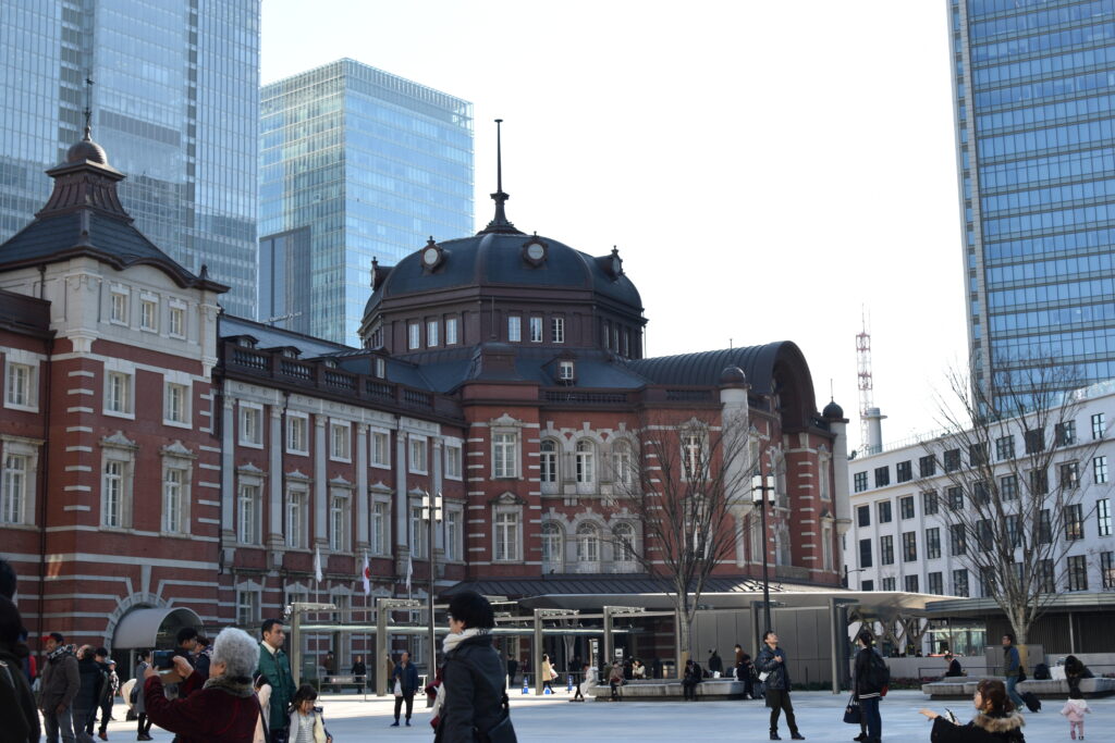 Red-brick Tokyo Station facade with a domed roof beneath a clear blue sky.