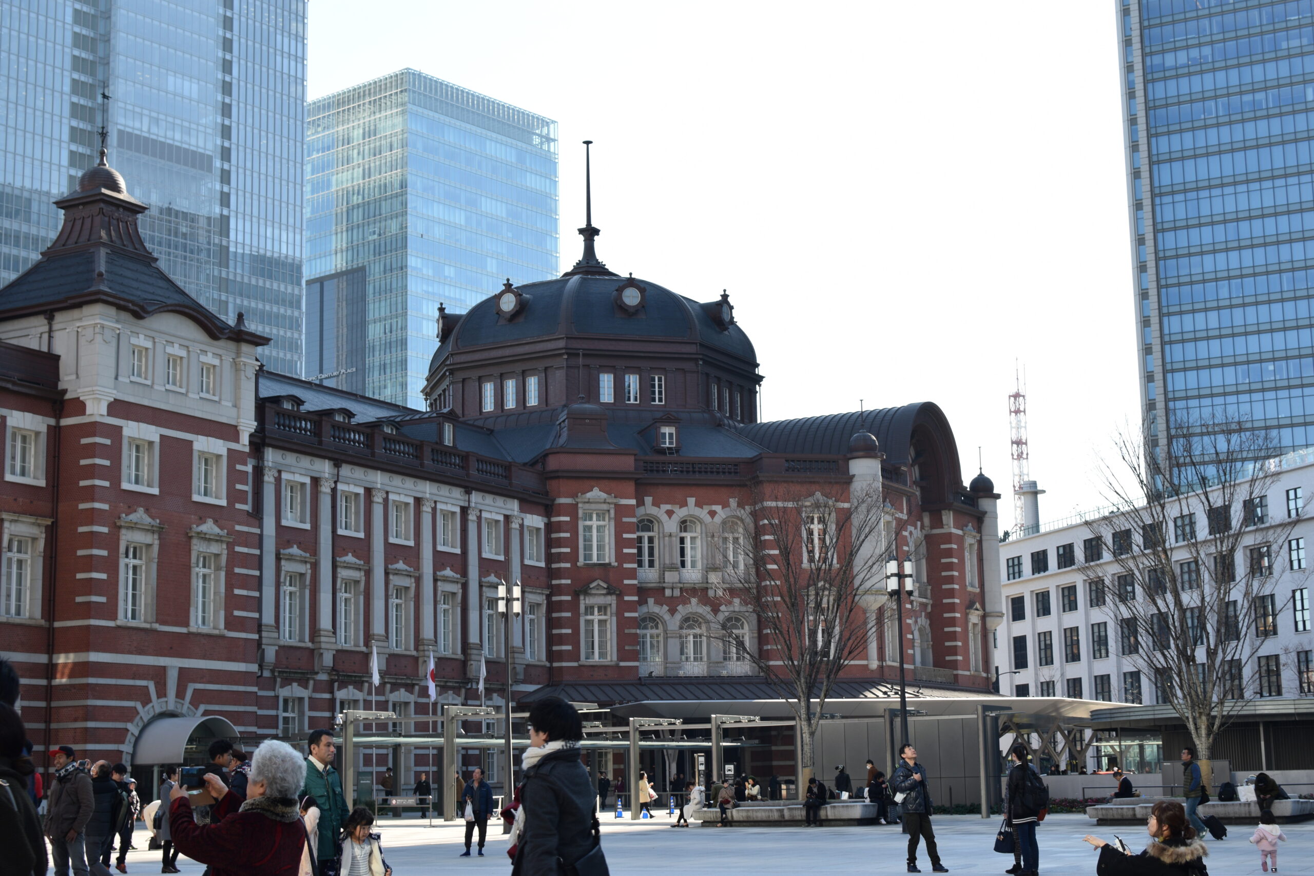 Red-brick Tokyo Station facade with a domed roof beneath a clear blue sky.